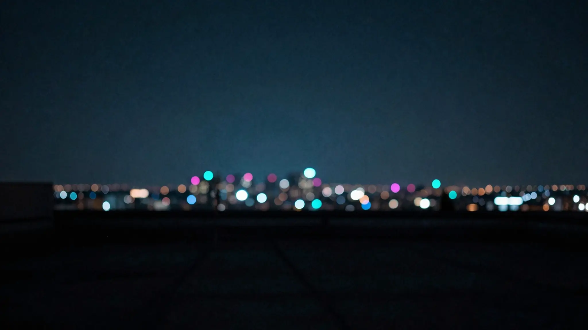 Out-of-focus teal and magenta city lights under a deep night sky
